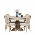 Dining room with a round wooden table and four chairs against a white wall.
