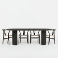 Dining room with a black oval table and chairs, featuring decorative items and a wall art piece.